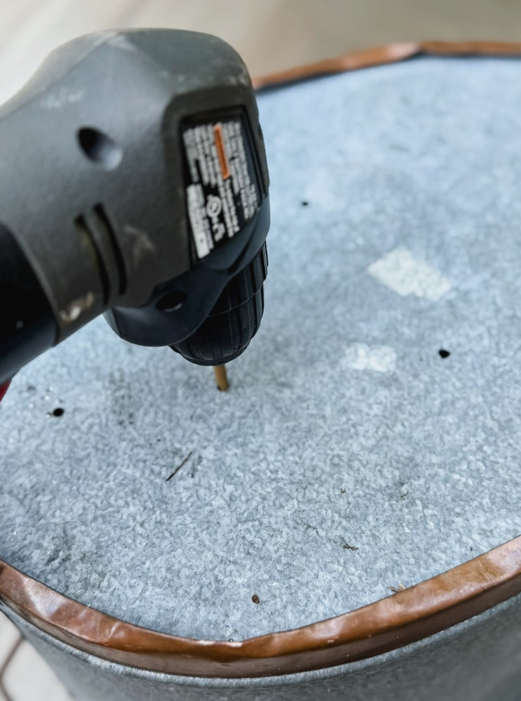 drilling holes in the bottom of a metal tub