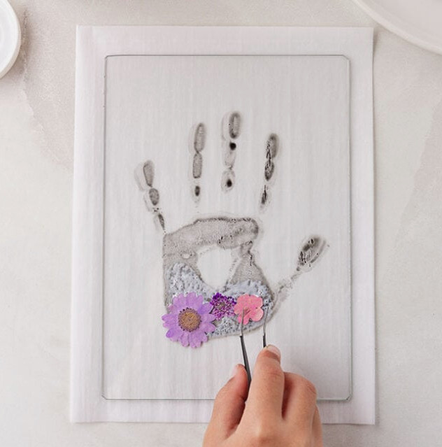 Add pressed flowers to handprint