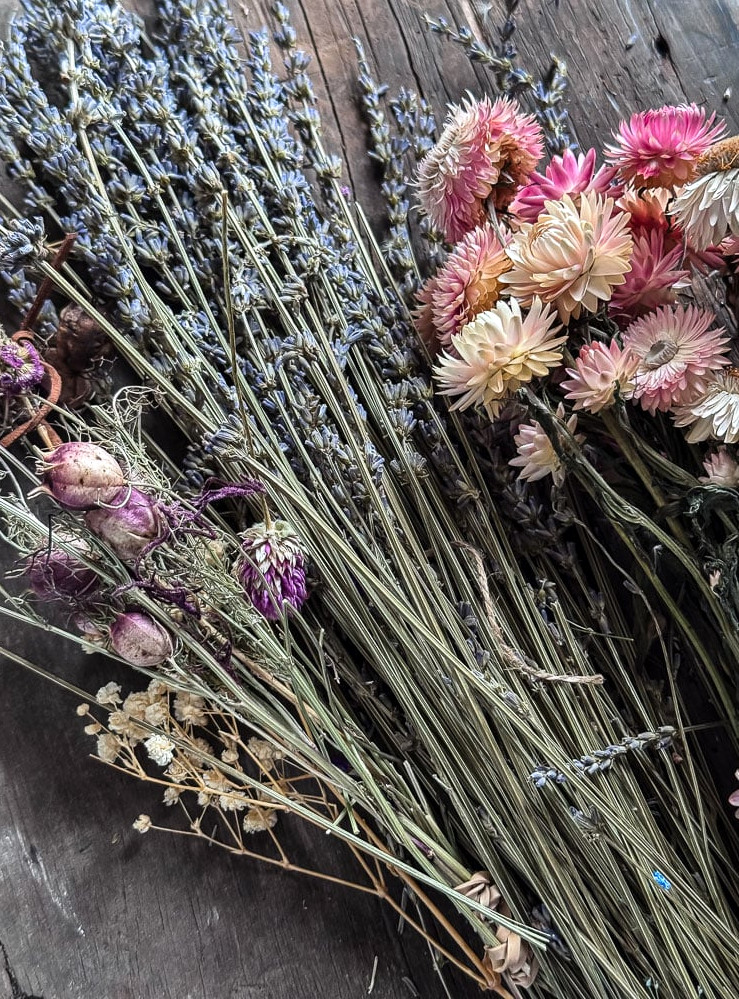bundles of dried flowers, including lavender and strawflowers, arranged on a table