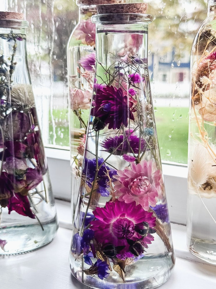a glass bottle filled with flowers suspended in oil