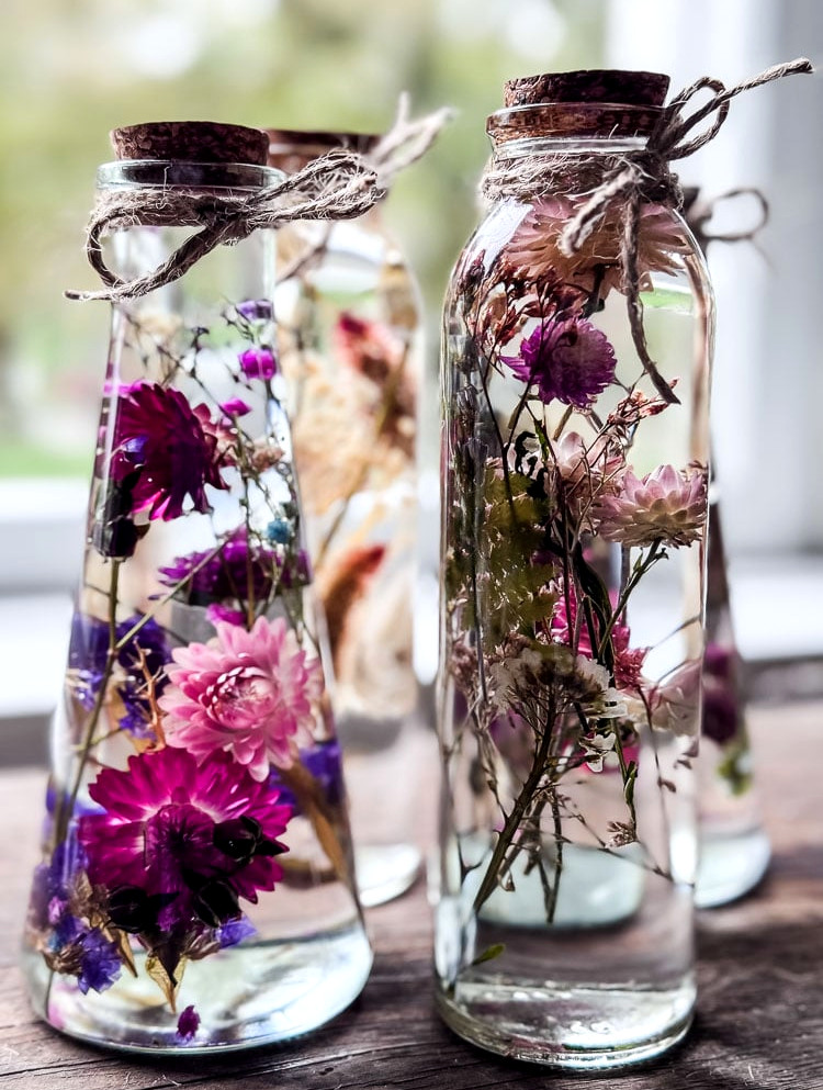 glass bottles with flowers suspended in oil in bright colors