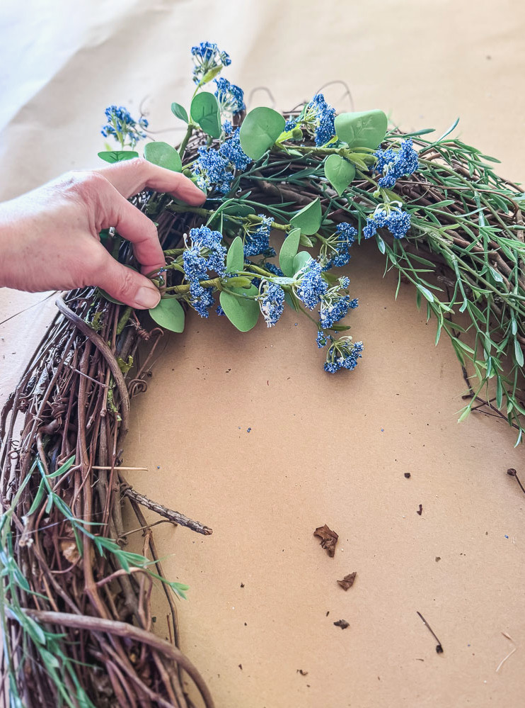 blue floral stem being added to a wreath