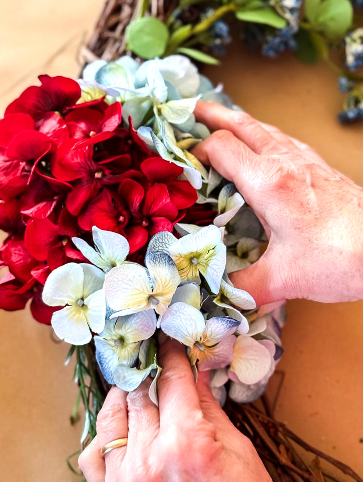 gluing blue hydrangeas to a wreath