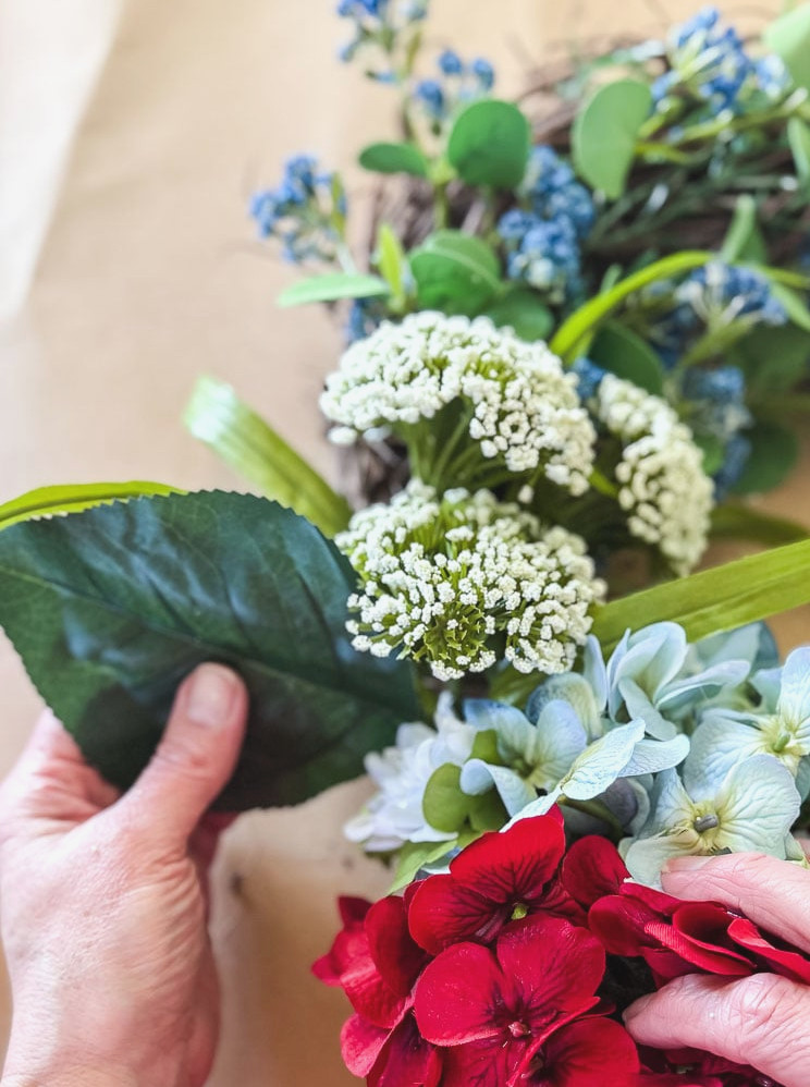 tucking a hydrangea faux leaf into a wreath