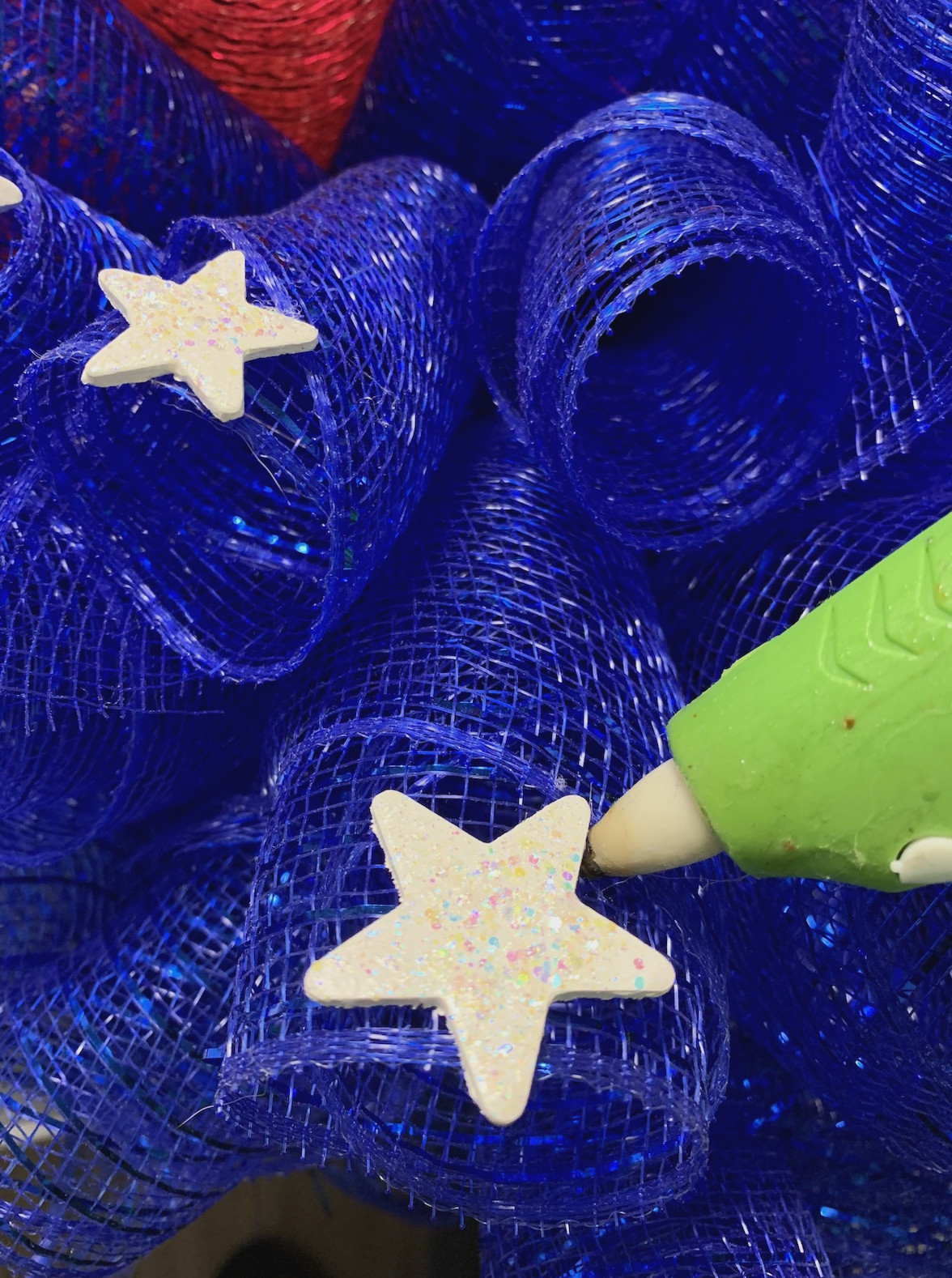 Hot gluing stars to a deco mesh wreath