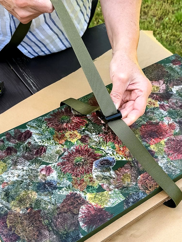 a woman's hand holding a green nylon strap on a flower press