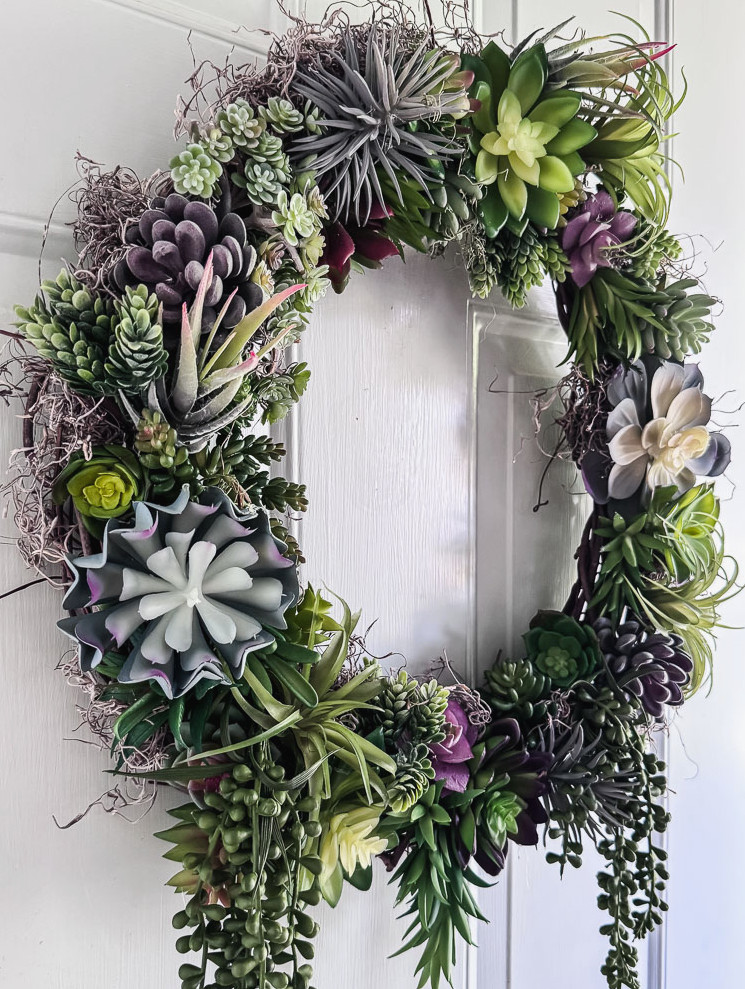 artificial succulent wreath hanging on a light blue door