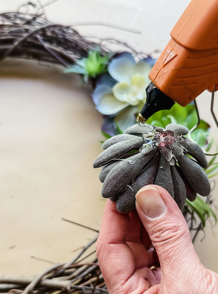hot gluing a fake succulent to a wreath
