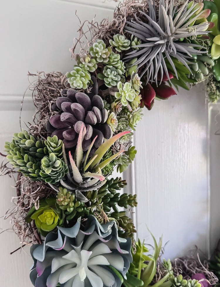 an artificial succulent wreath on a light blue door