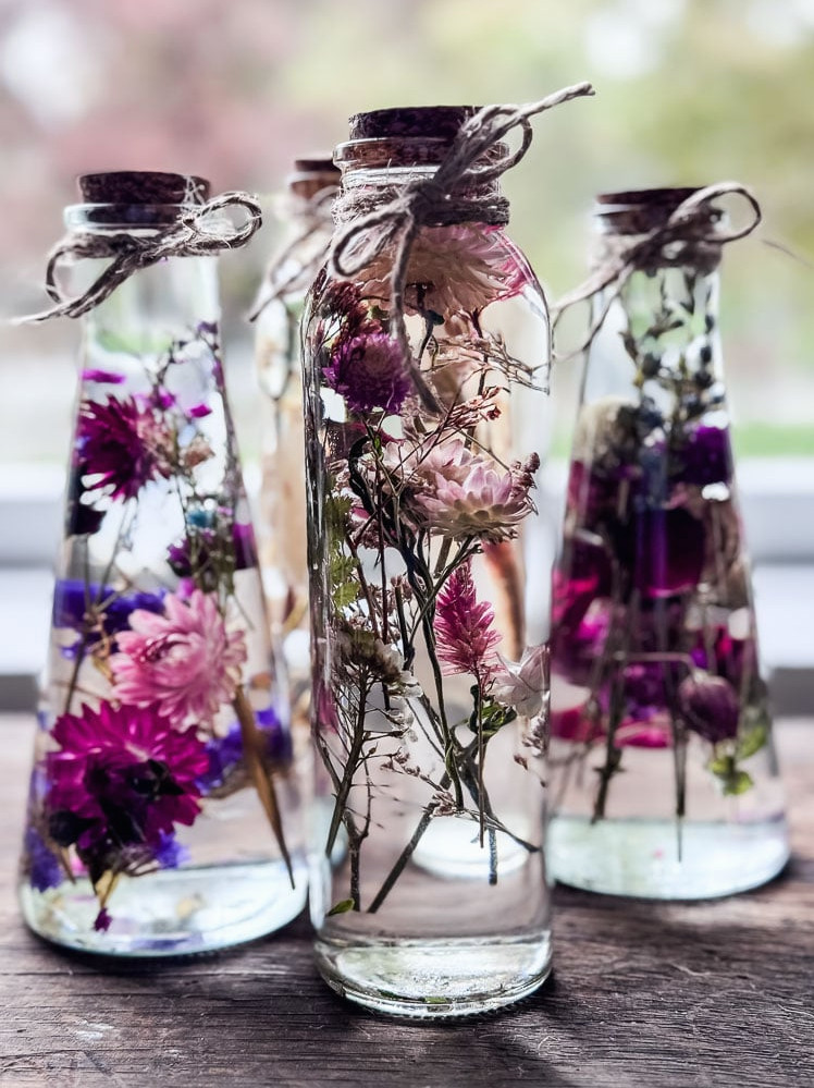 3 bottles of flowers suspended in oil
