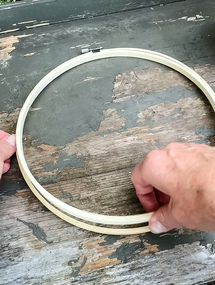 opening up an embroidery hoop on top of a chipped green table